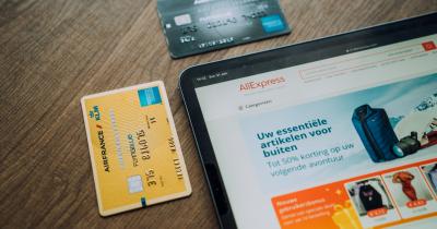 Picture of a tablet sitting on a table with two credit cards displayed on the table