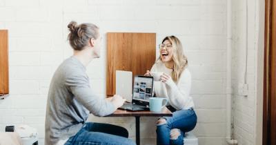 Two people laughing over laptop
