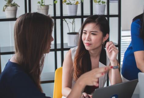 Two women chatting in front of a computer