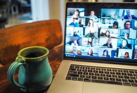 Picture of an open laptop with a Zoom meeting and a coffee mug next to it