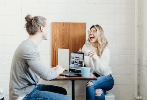 Two people laughing over laptop