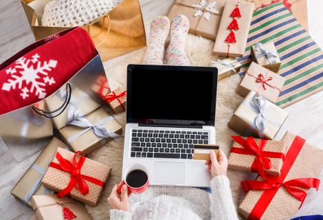 Girl with credit card on laptop surrounded by gifts